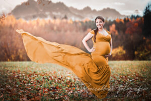 Babybauch-Fotografie Augsburg – Schwangere im goldenen Kleid beim Outdoor-Shooting