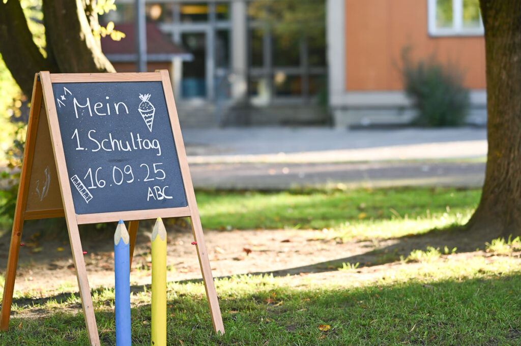 Schultafel mit Aufschrift ‚Mein 1. Schultag 16.09.25‘ im Garten der Grundschule Herbertshofen – kreatives Set für Schulfotografie von Preiselbeer-Fotografie
